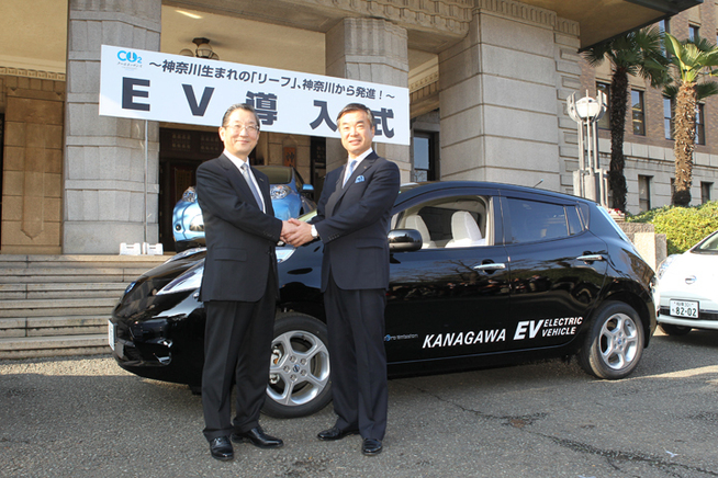 電気自動車「リーフ」を前に握手を交わす日産　志賀COOと松沢 成文 神奈川県知事　画像